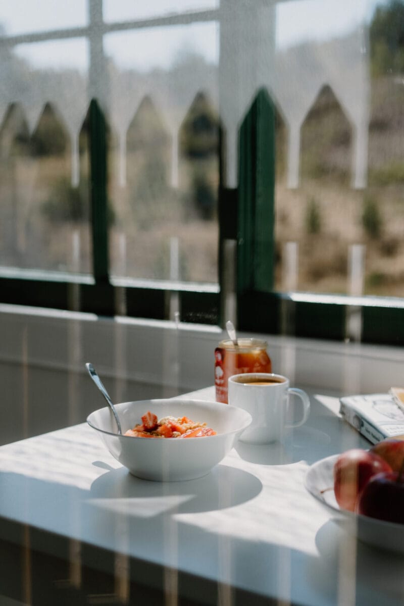 Breakfast table set beside tall windows at Cairn Valley Cottage, Rothiemurchus, Aviemore