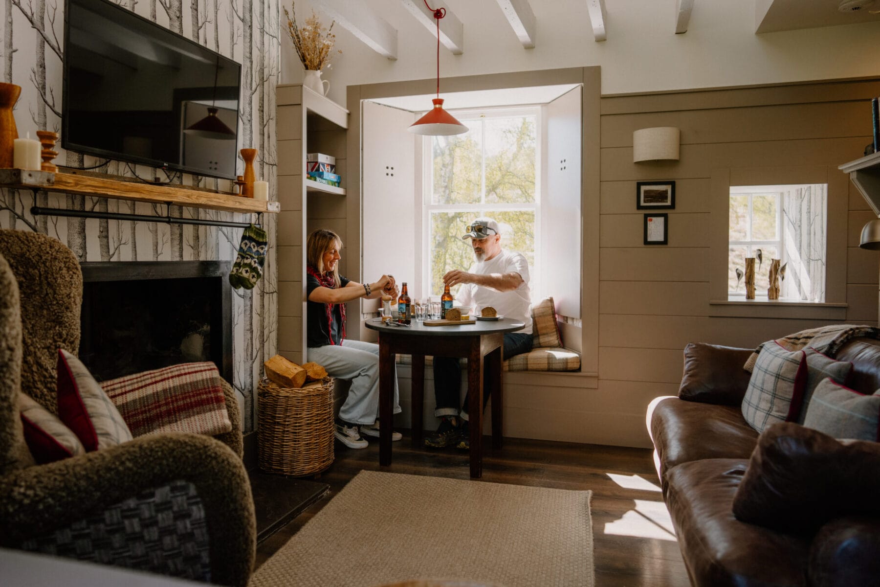 Living and dining room with fireplace and window nook at Cairn Valley Cottage, Rothiemurchus, Aviemore
