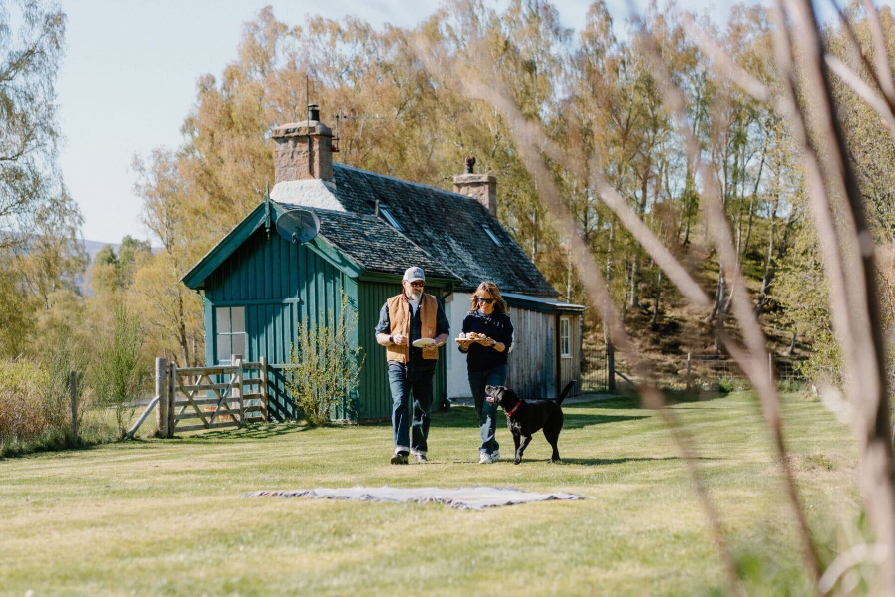 Couple outside the green timber garden room at Cairn Valley Cottage, Rothiemurchus, Aviemore