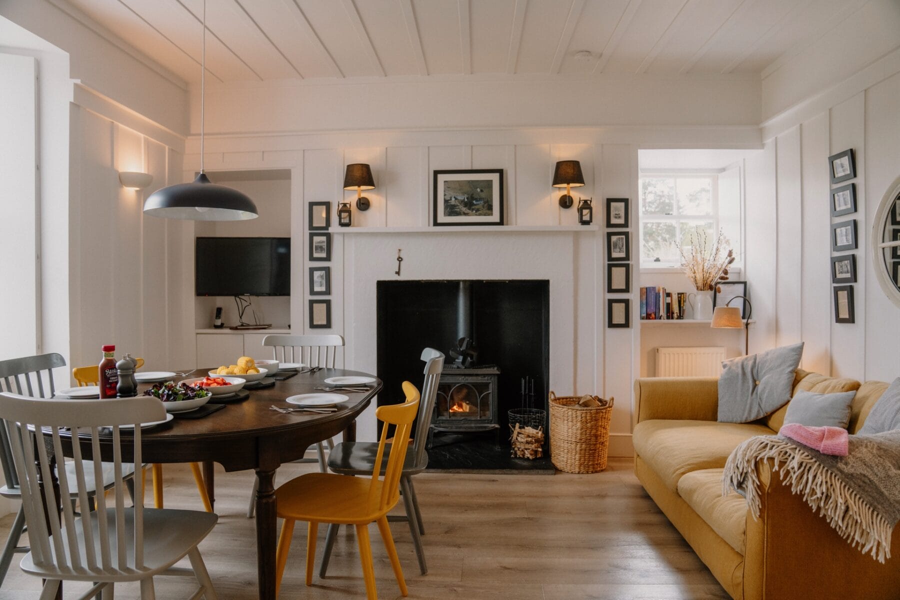 Living and dining room with fireplace and sofas at Achnahatnich House, Rothiemurchus, Aviemore