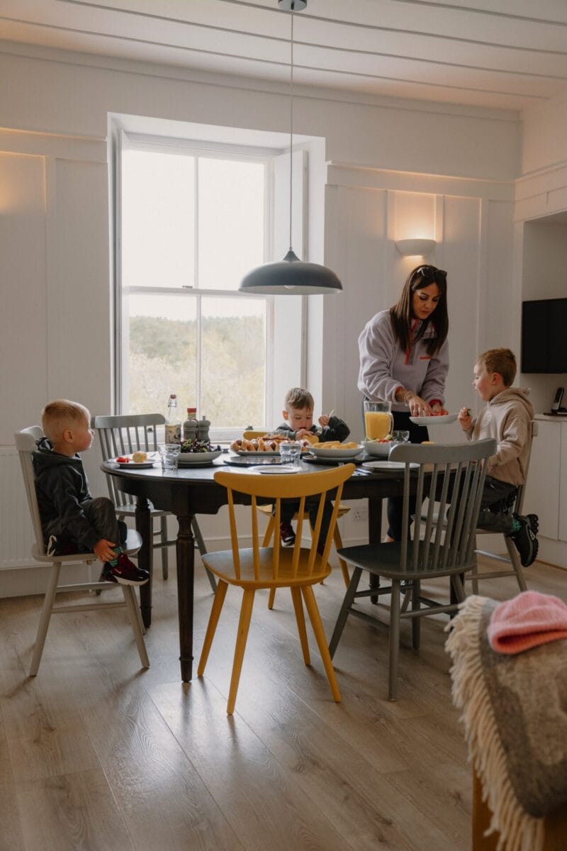 Family gathered around the dining table at Achnahatnich House, Rothiemurchus, Aviemore